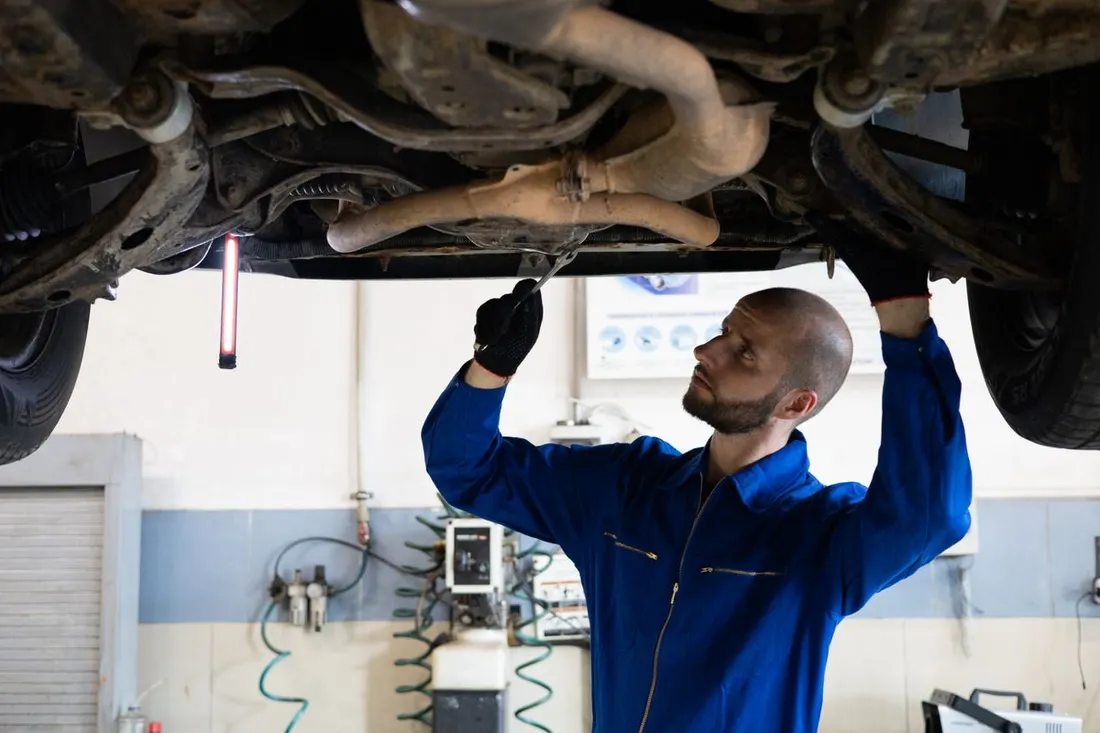Illustrative mechanic inspecting a passenger car on a lift