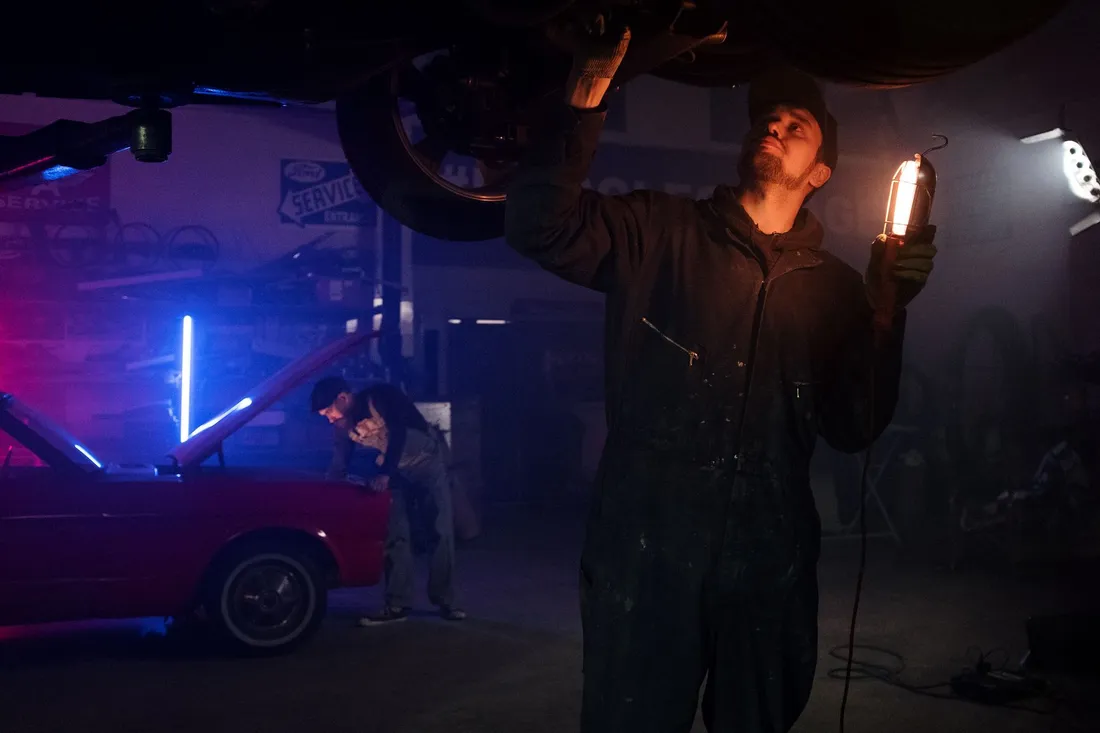 Illustrative mechanic examining the underside of a vehicle