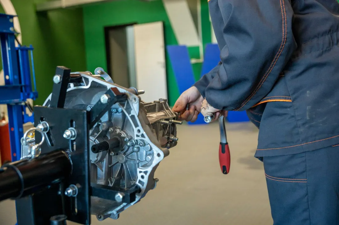 Illustrative mechanic working on removed transmission components
