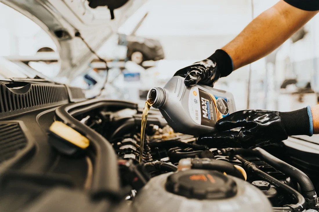 Illustrative close view of fresh oil being poured into a car engine
